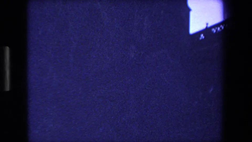 The camera tilts downward or drifts, leaving only a partial cathedral edge and small blue sky area visible above a mostly dark, grainy field.