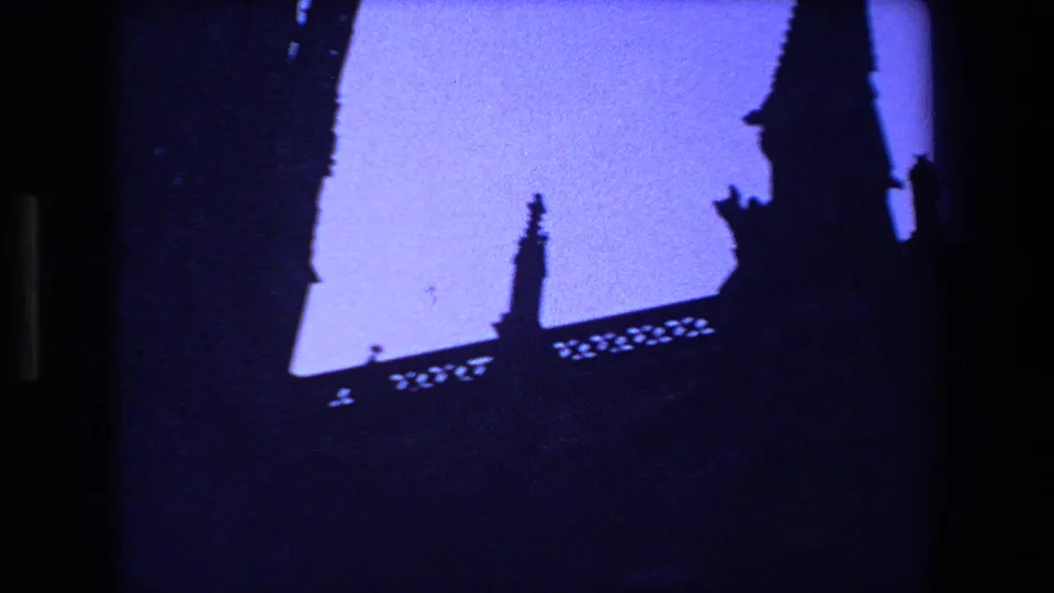 A silhouetted Gothic church tower and decorative roofline appear against blue dusk light in this 1970 Strasbourg 8mm home-movie frame, with dark exposure and visible film texture.