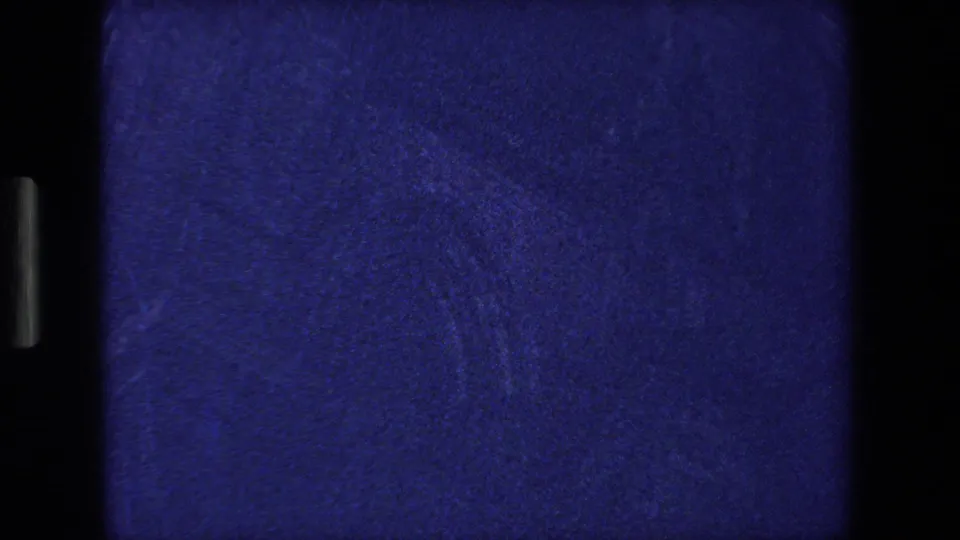 Blue-tinted opening frame from scanned 8mm footage, with little scene detail visible beyond film texture, gate edges, and dark vertical borders.