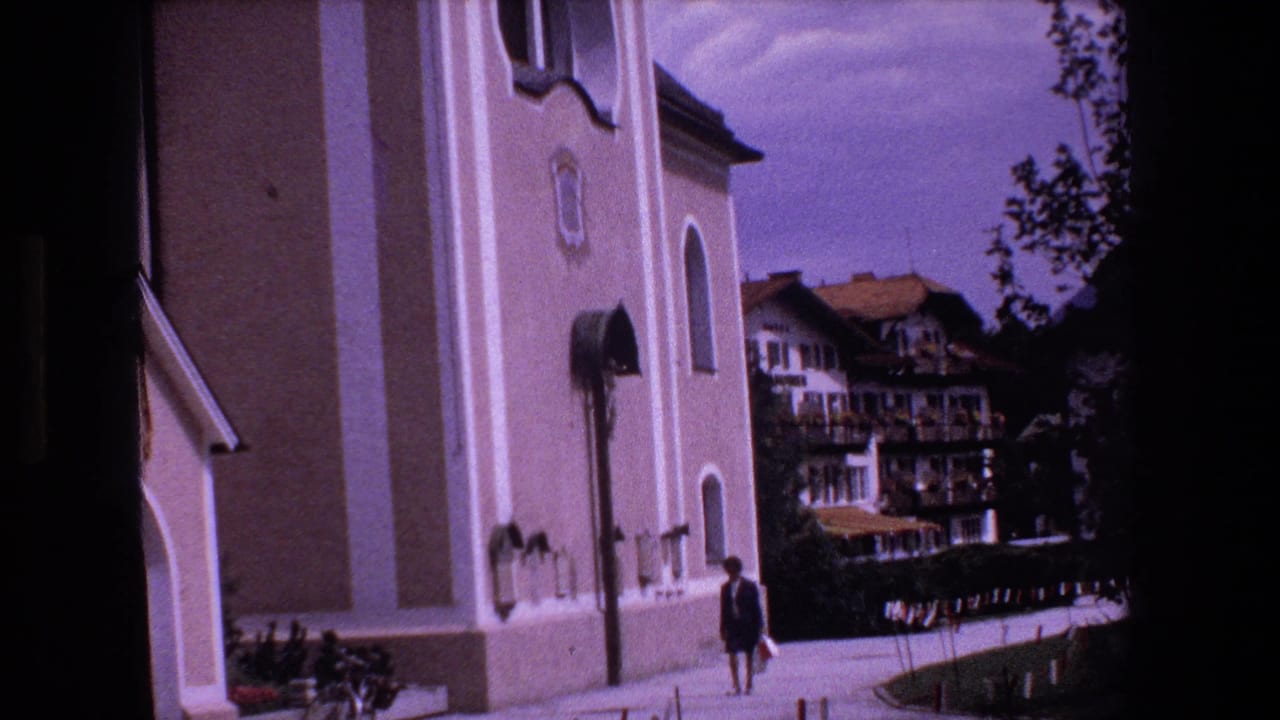 A person walks along the church-side path with residential buildings in the background.