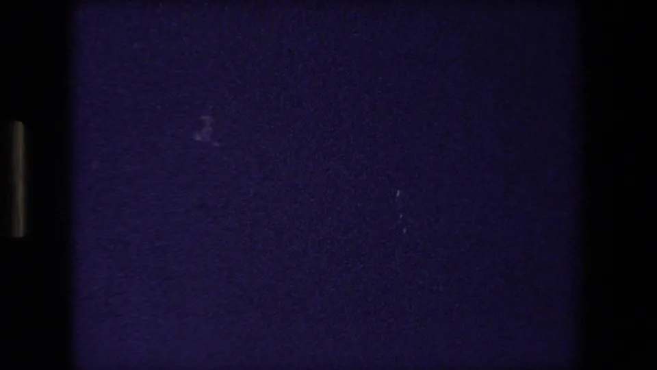 Underexposed 8mm frame from the Strasbourg church clip, mostly dark with purple grain and faint marks visible in the film image.