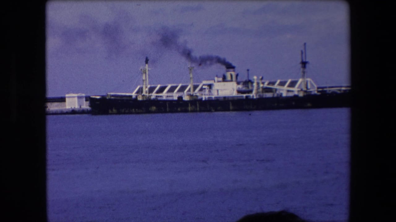 Large ship at pier emitting dark smoke from its funnel.