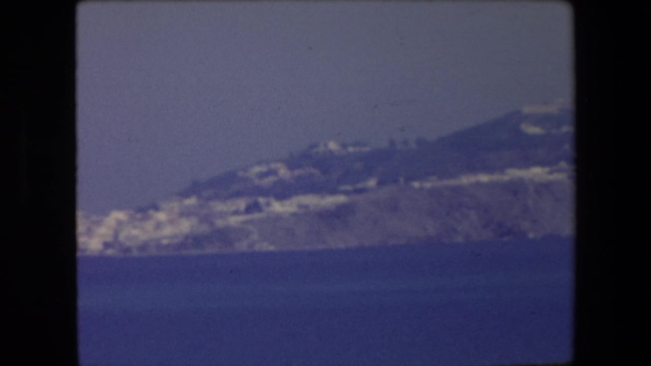 1971 Algeria frame with a soft, blue-tinted view of a coastal hillside and white buildings seen from across open water.