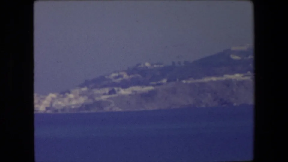 1971 Algeria frame with a soft, blue-tinted view of a coastal hillside and white buildings seen from across open water.