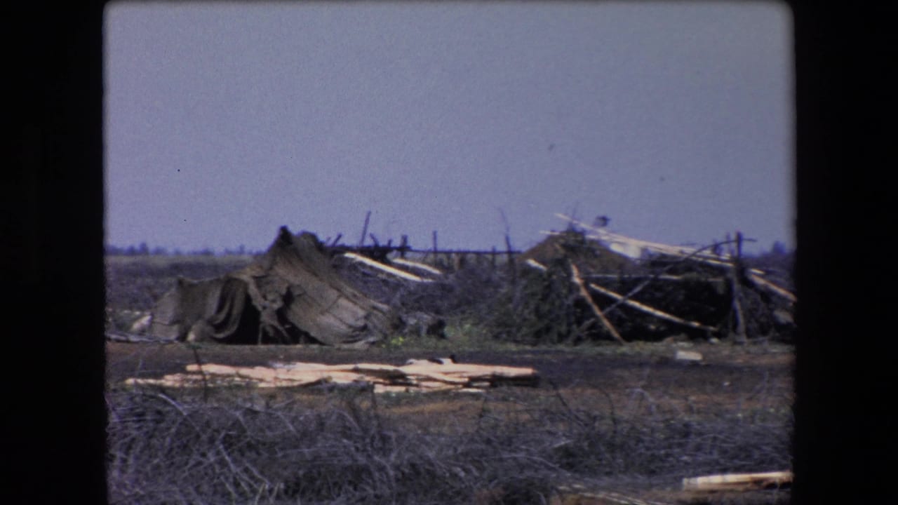 Damaged canvas, poles, and debris sit across a barren open area.