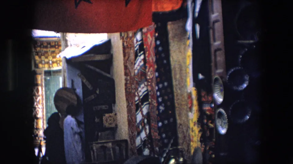 The final frame shows a narrow Algerian market alley with patterned textiles, visible shop signage, speakers, and a person near a doorway.