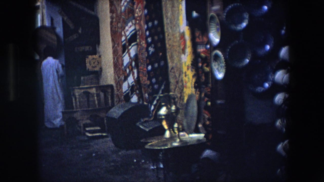 Market stall area with textiles, metalware, baskets, and a figure in light clothing.