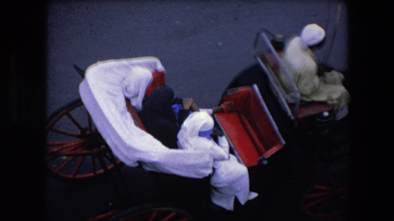 1971 Algeria frame showing the white-draped carriage moving past a second carriage, with passengers seated inside and a driver in a light garment and turban ahead.