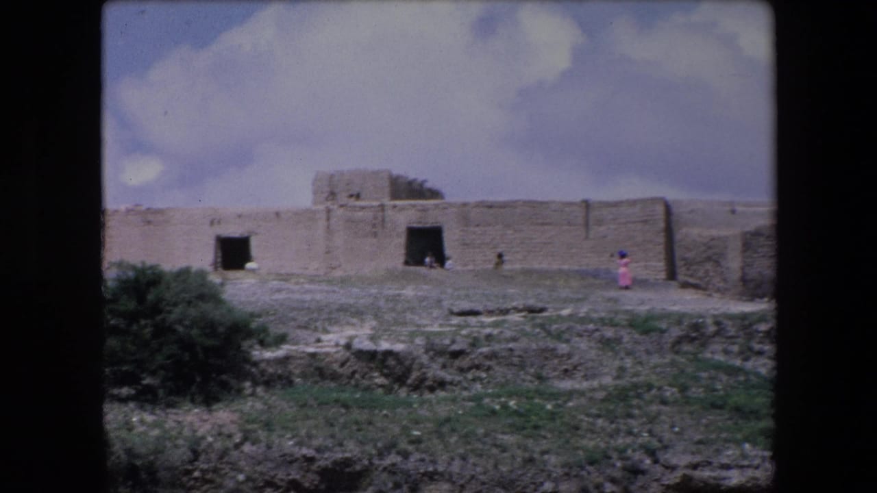 Wide view of stone building with a small person in pink walking nearby.