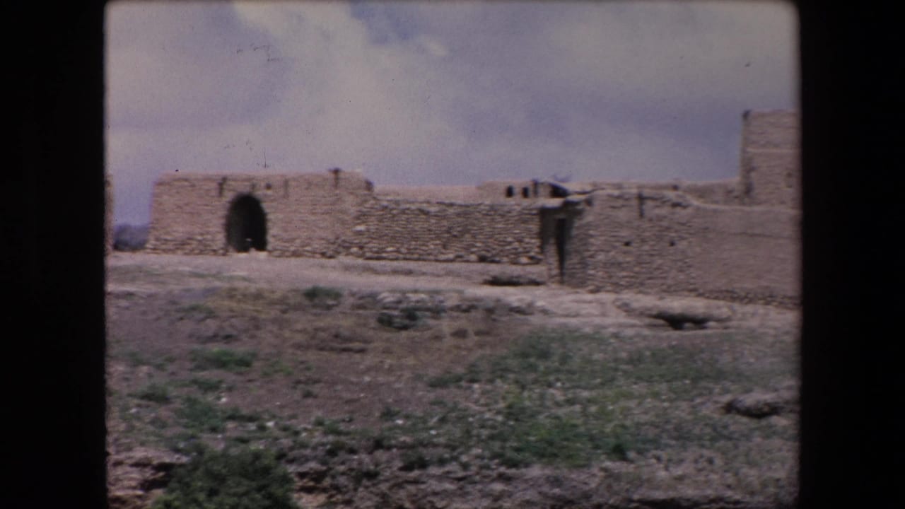Low desert fort wall with central arched opening and uneven stonework.
