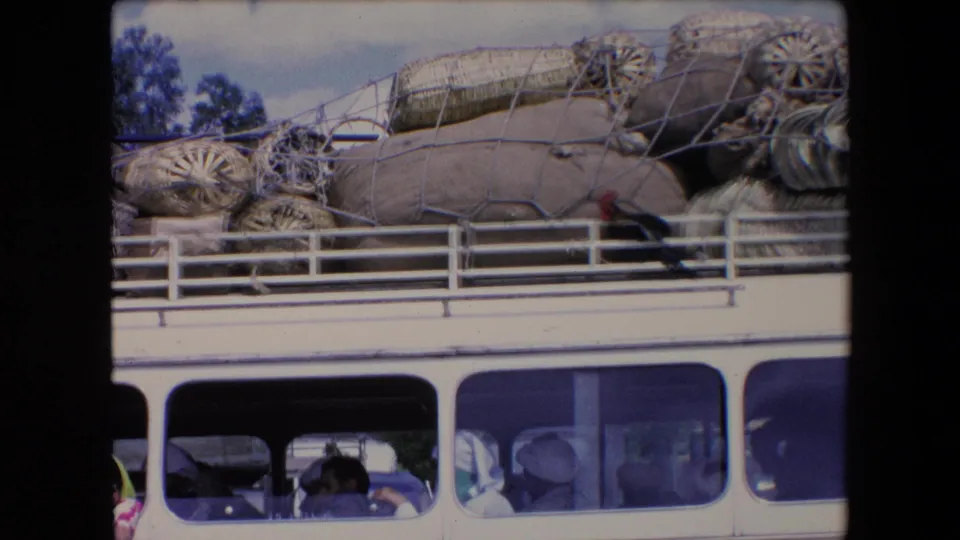 A bus in Algeria, dated by metadata to 1971, appears crowded with bundled roof cargo while passengers sit behind the windows below.
