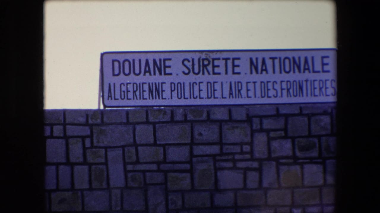 Official Algerian customs and national security sign framed above a stone wall.