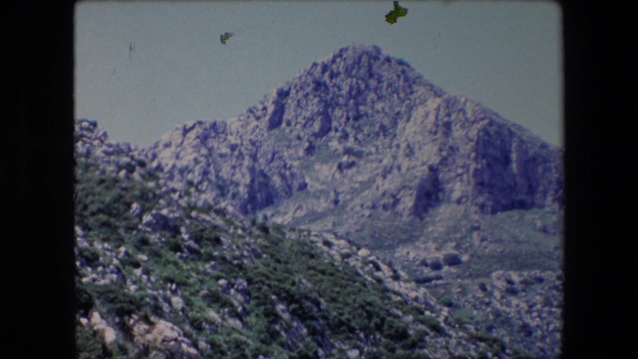 Rugged mountain peak and rocky hillside with dense green shrubs.