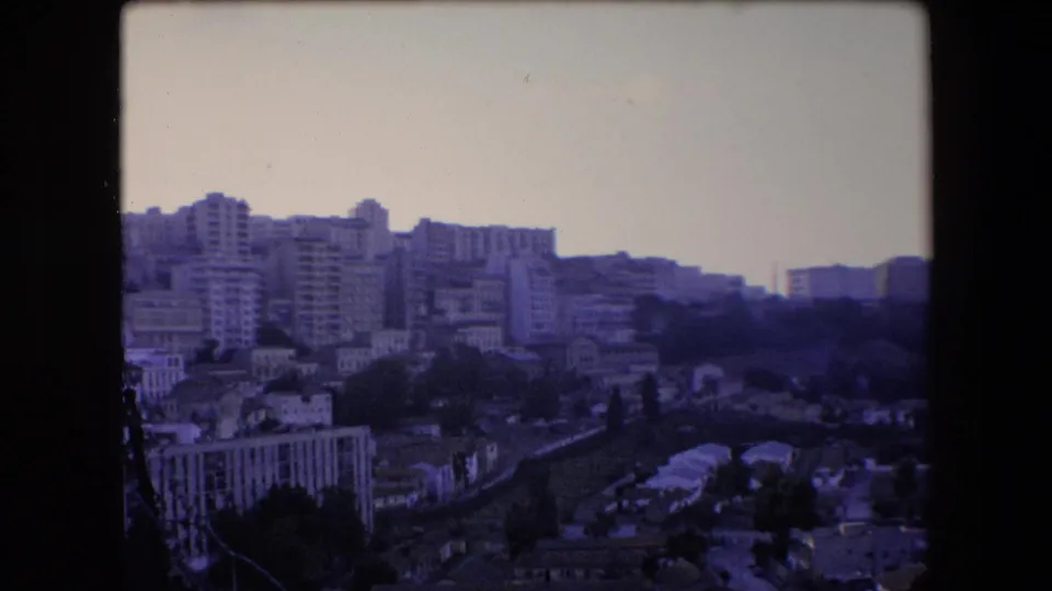 Elevated 1971 Algeria city view with apartment towers and residential structures spread across a hillside under a washed, pale sky.