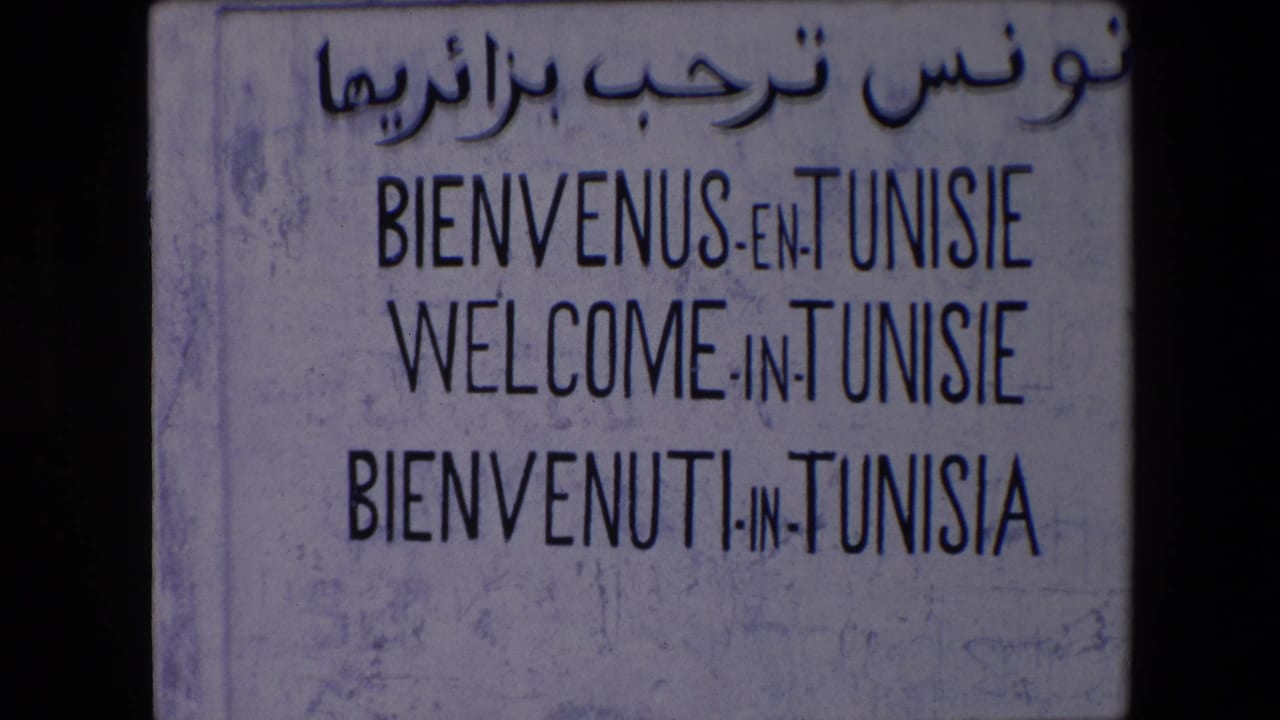 1971 Algeria travel footage showing a weathered welcome sign for Tunisie with Arabic script above French, English, and Italian lines.