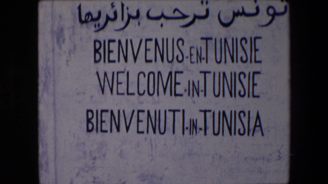 Lower framed view of the multilingual Tunisie welcome sign with visible weathering.