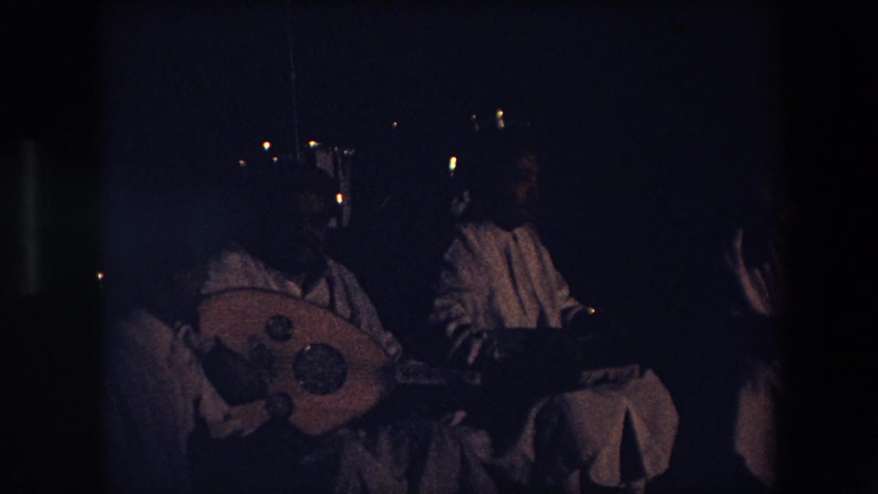 Closer dark frame of musicians with a large stringed instrument in the foreground.