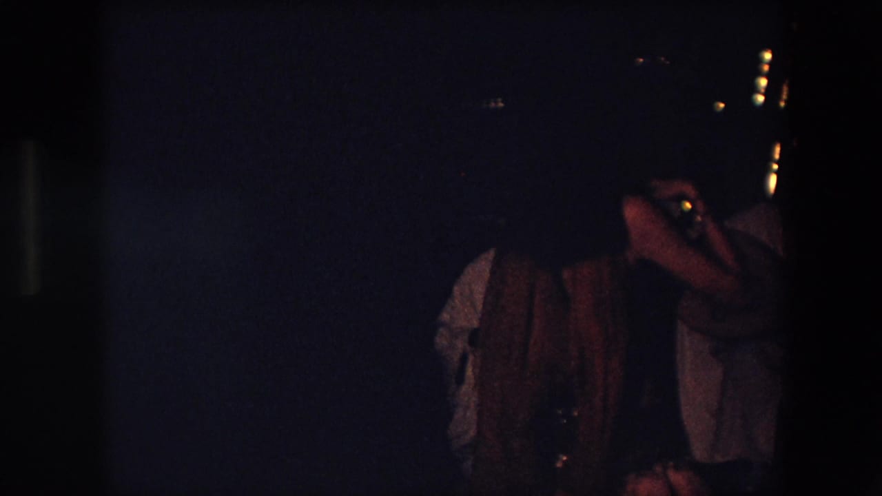 Partially obscured performer and nearby figure in a dark venue.