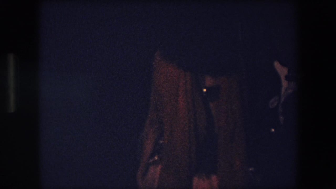 Dancer seen from behind or side in very low light with a dark background.