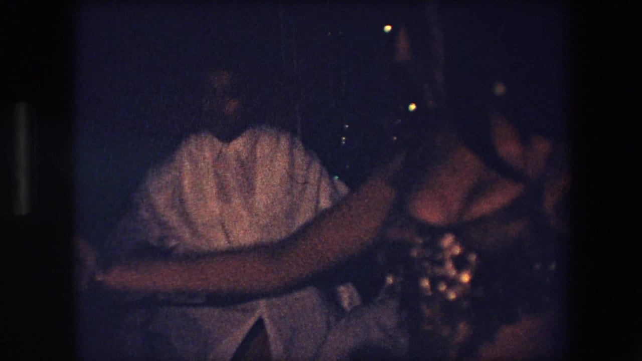 Dancer and nearby musician or attendee appear in a dark performance space.