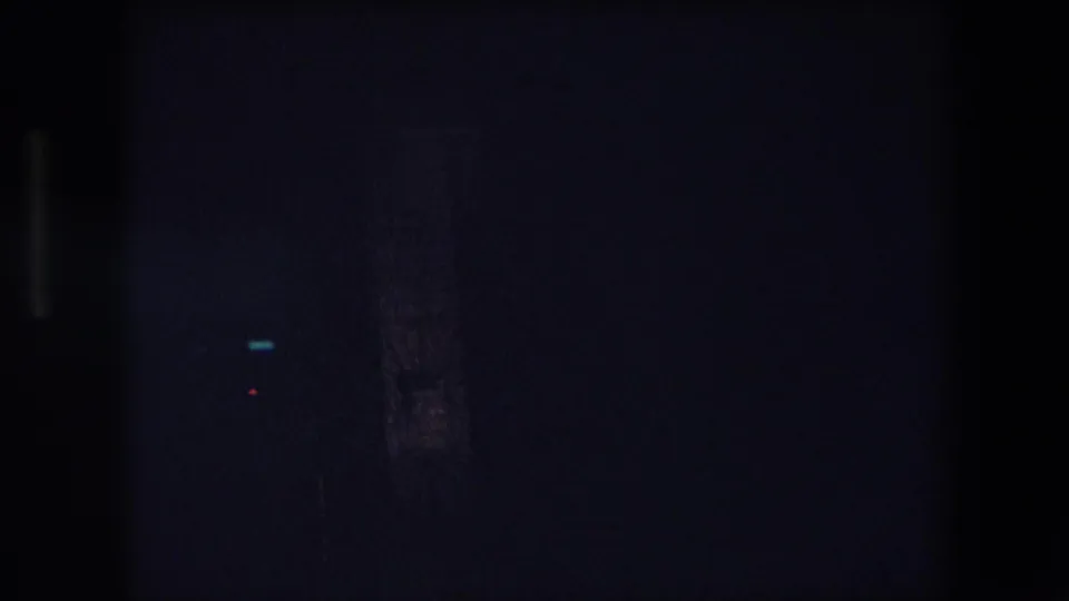 Low-light 8mm frame from a nighttime drive in Barcelona, showing small bright light points and indistinct vertical city forms.