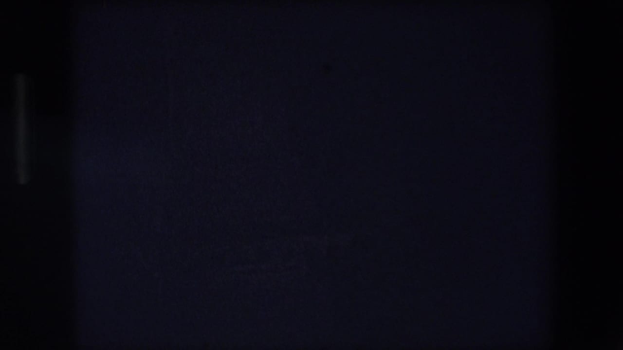 Dark surface with a central vertical shadow and faint illuminated marks.