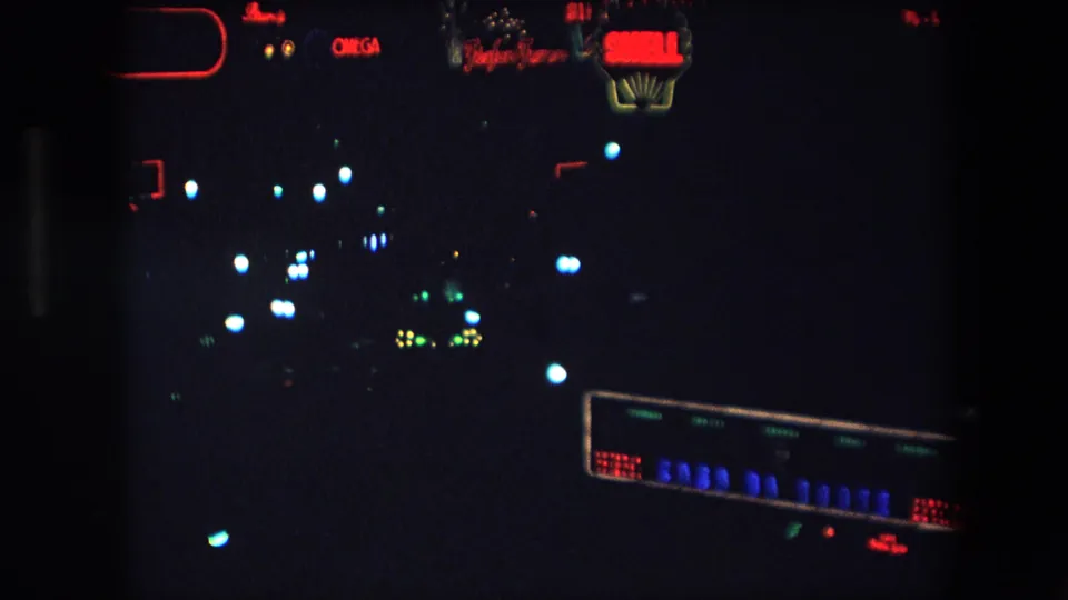 1971 Barcelona frame showing red neon commercial lettering near the top and blurred street or building lights below in an underexposed night view.