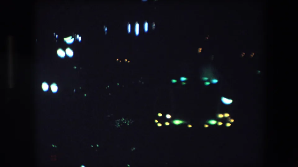 1971 Barcelona 8mm frame showing soft nighttime city lights from a fixed elevated viewpoint, with no identifiable people or landmarks.
