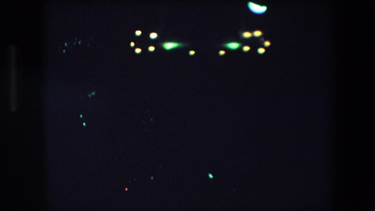 Dark frame with bright green and yellow lights near the upper right.