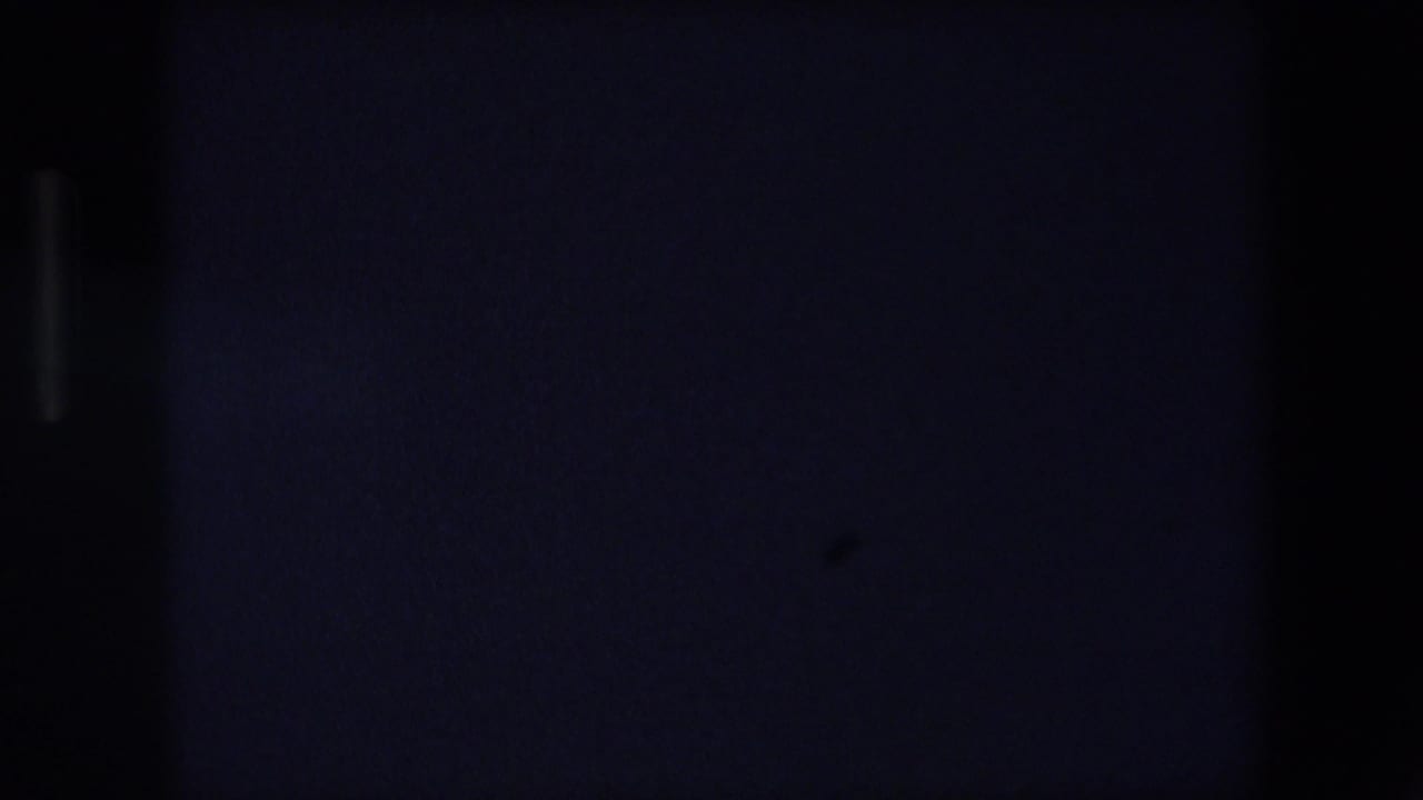 Very dark 1971 Barcelona home-movie frame with scattered distant lights and little visible structure beyond the low-light urban scene.