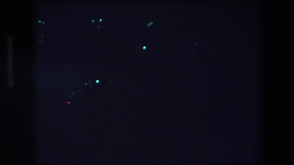 Low-light 1971 Barcelona frame showing small blue-white and red points that appear to be distant traffic or city lights.