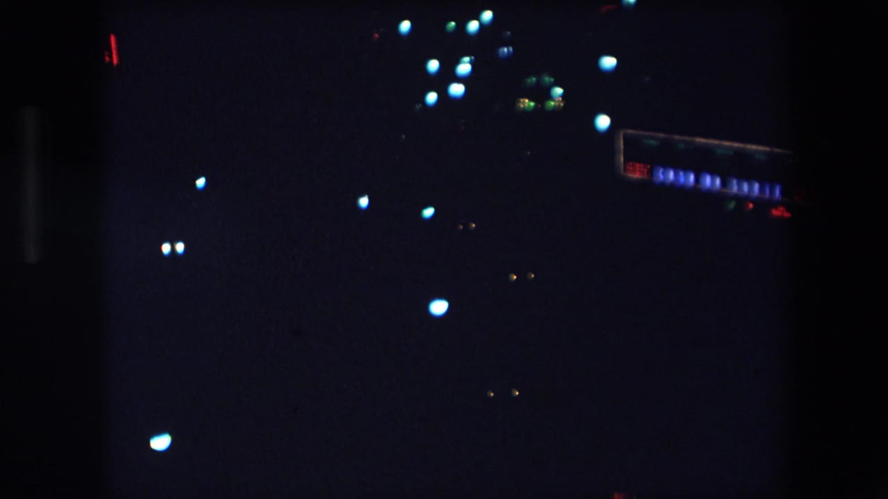 1971 Barcelona 8mm night footage showing scattered blue-white and amber light flares against a mostly black urban scene.