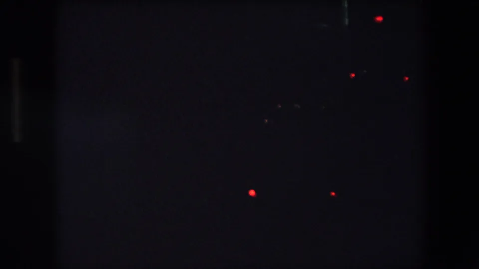 1971 Barcelona 8mm frame with scattered red and green points of light in a very dark low-exposure night view, with no identifiable figures or structures.