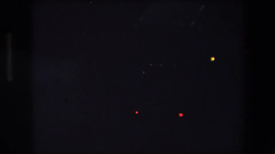 Underexposed 1971 Barcelona home-movie frame showing distant vehicle lights against a nearly black nighttime roadway.