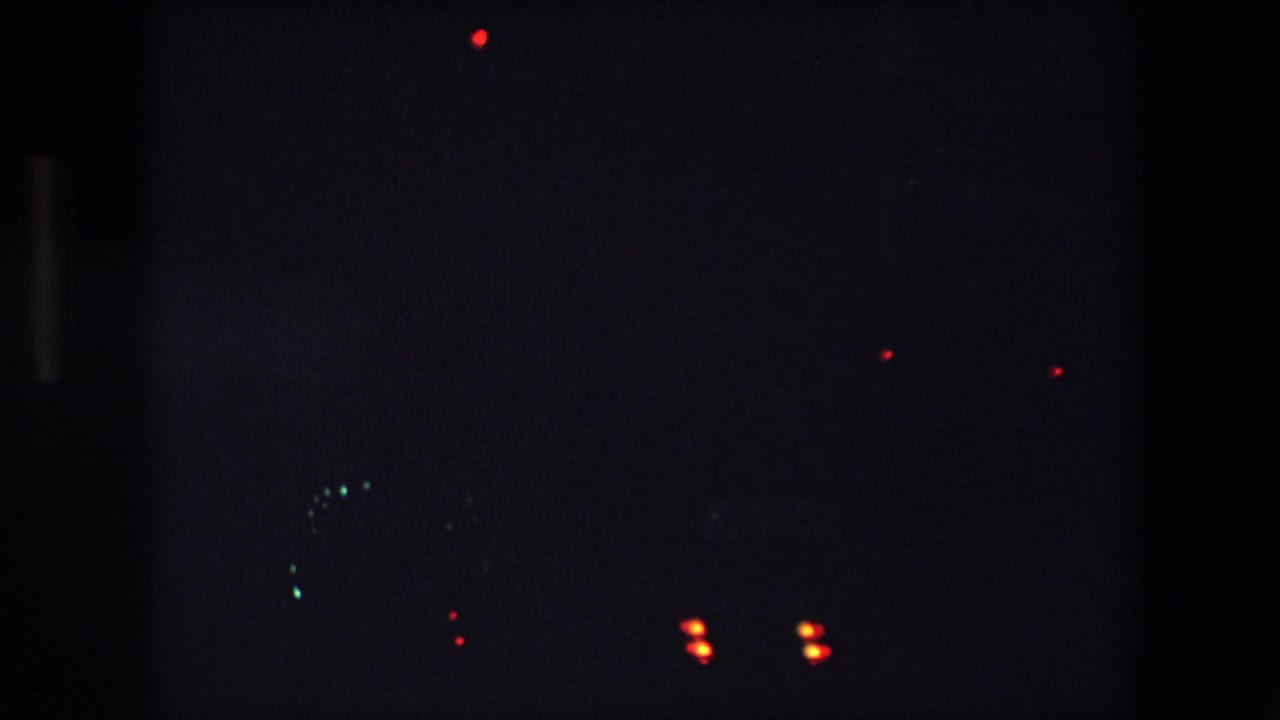 Night freeway view from the Barcelona 1971 footage, with red tail lights and faint greenish headlights or reflections in deep shadow.