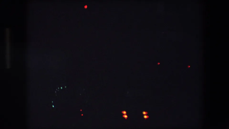 Night freeway view from the Barcelona 1971 footage, with red tail lights and faint greenish headlights or reflections in deep shadow.