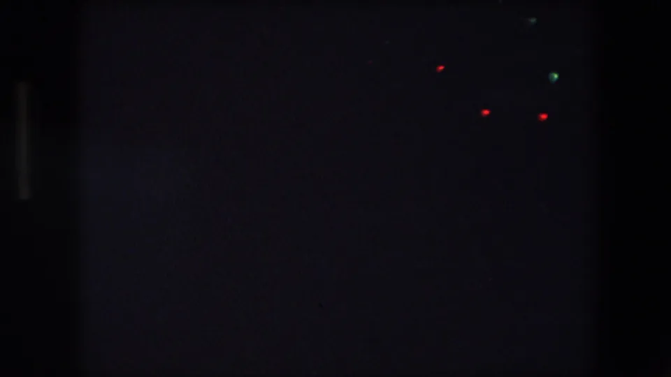 Archival 8mm night-driving frame from Barcelona, showing sparse vehicle lights across a largely black road scene.
