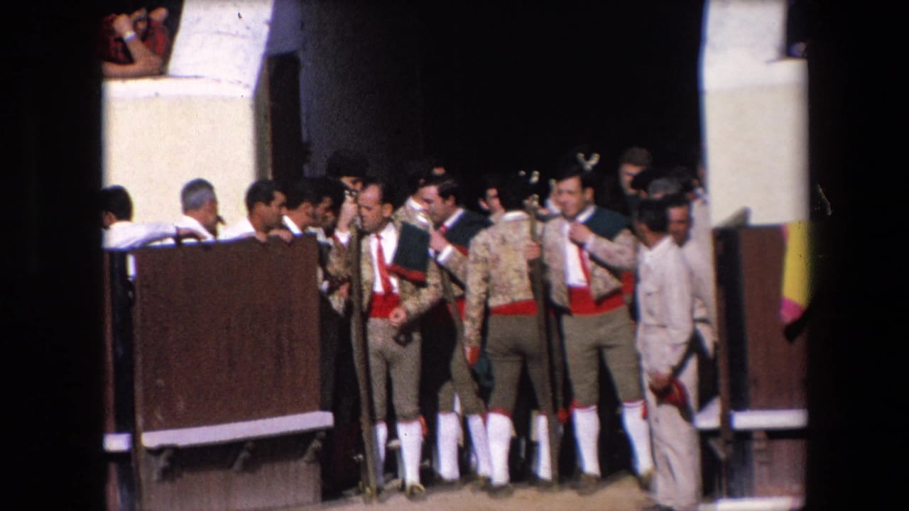 In supplied 1971 Barcelona footage, matadors in embroidered jackets, red sashes, and white socks stand with staffs near an open bullring gate while spectators watch.