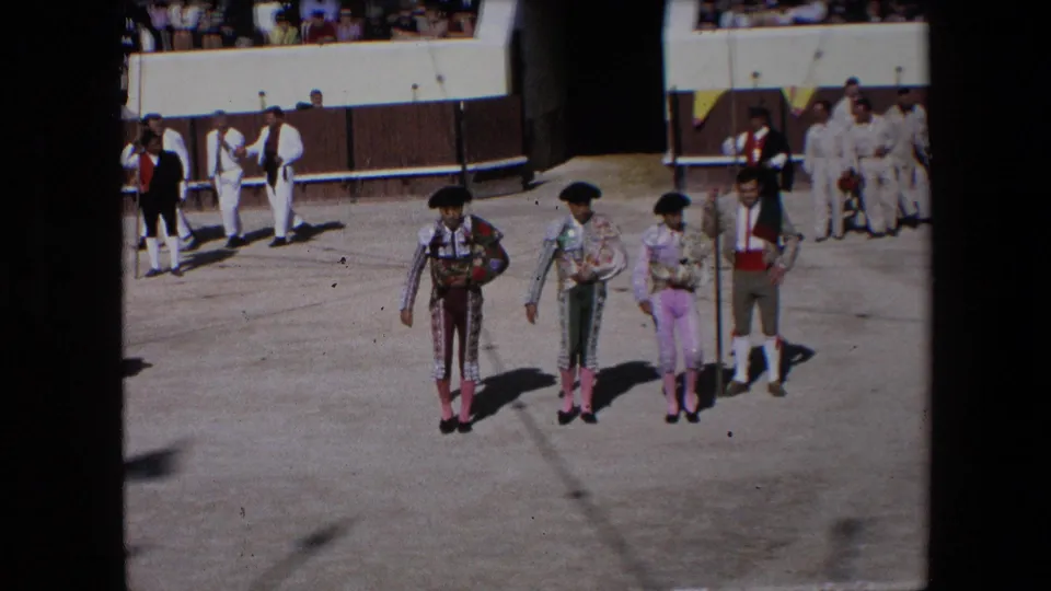 Three bullfighters in trajes de luces gather near the arena edge in 1971 Barcelona, with attendants in white and spectators visible behind the barrier.