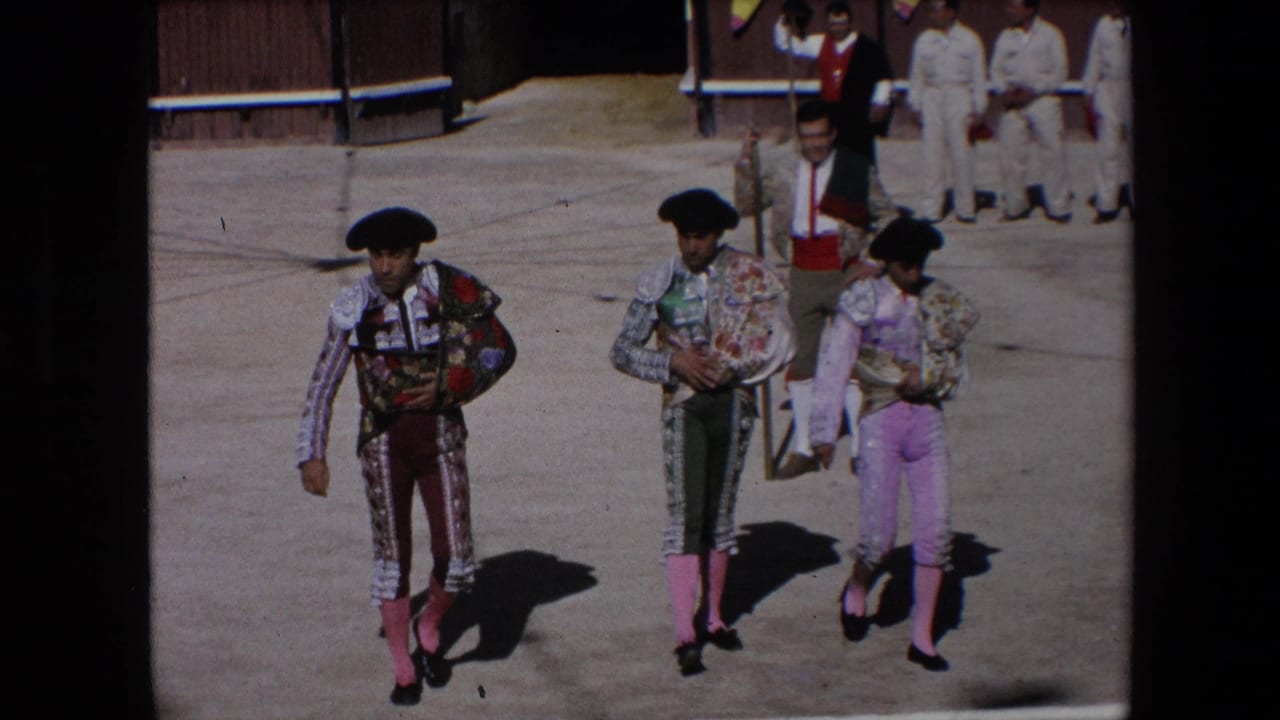 In Barcelona, Spain in 1971, three matadors in ornate trajes de luces and black monteras walk across a bright bullfighting arena floor with attendants in the background.