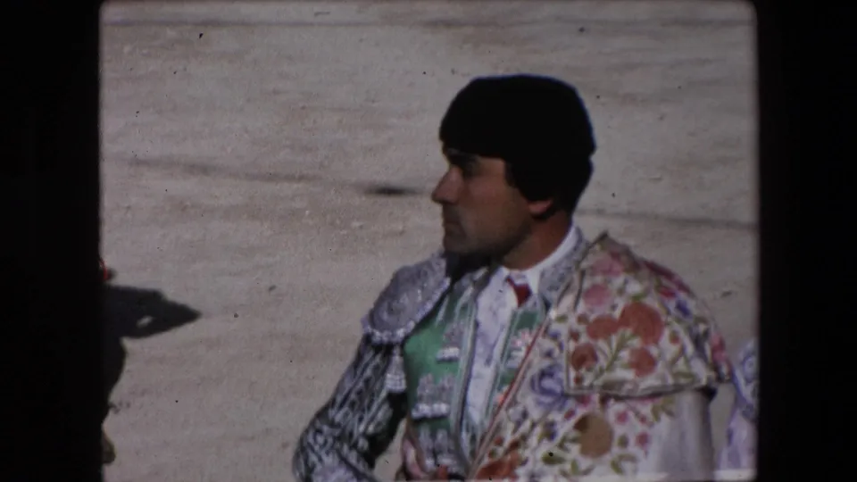A profile view in the 1971 Barcelona arena shows a matador wearing a black montera and richly embroidered traje de luces against the pale arena floor.