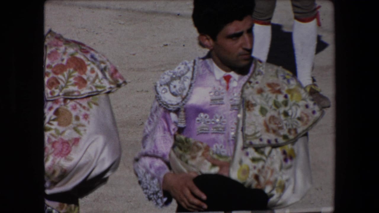 In Barcelona 1971 8mm footage, a matador in a purple and floral embroidered suit stands in partial close-up beside the sandy arena area.