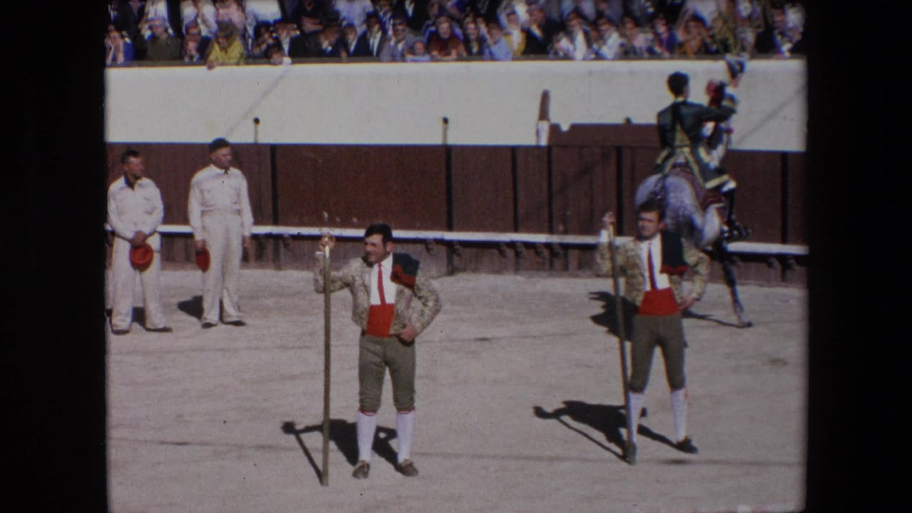 1971 Barcelona bullfighting arena view with two bullfighters in ornate jackets, a mounted participant, white-uniformed attendants, and spectators above the barrier.