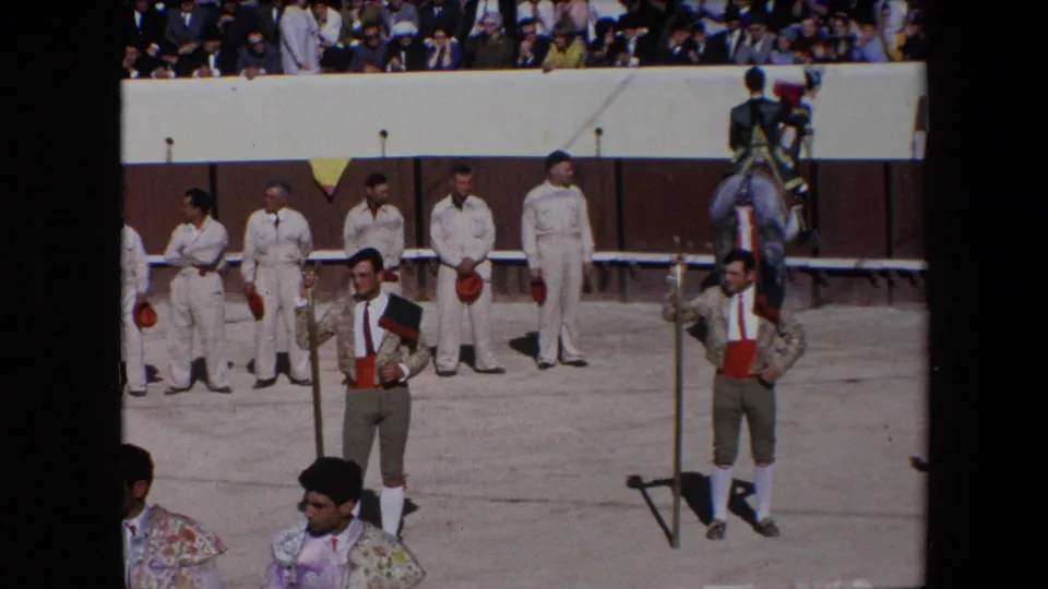 1971 Barcelona bullfighting scene showing a bullfighter holding a dark hat or case near attendants in white uniforms, with a mounted figure at the right edge.