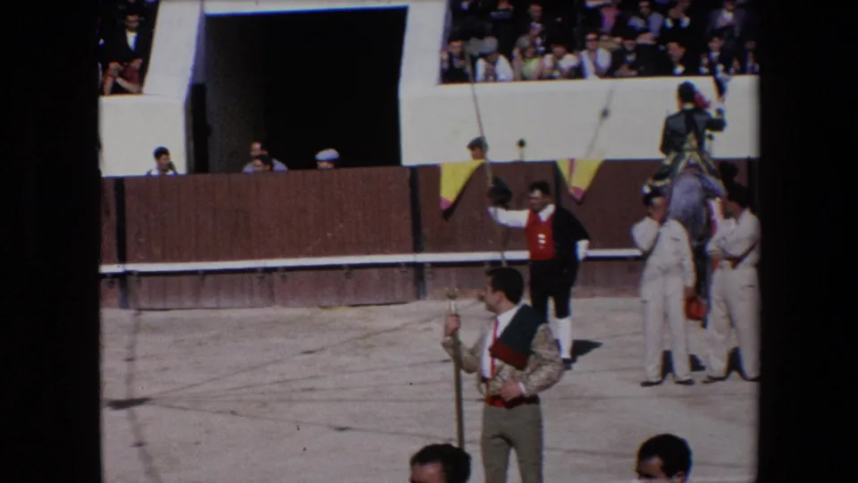 1971 Barcelona bullfighting arena view with a bullfighter raising an arm near the barrier, attendants in white uniforms, a mounted rider, and spectators in the background.