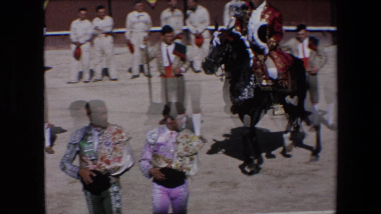 In Barcelona, Spain in 1971, matadors in ornate suits stand on the sandy arena floor while a rider on a decorated black horse moves near attendants by the ring wall.