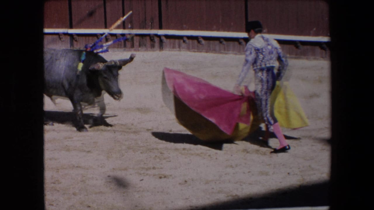 The 1971 Barcelona bullfighting footage shows the matador repositioning the red and yellow cape while the bull faces him from the left side of the sandy ring.
