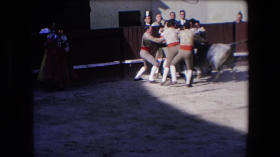 A group of attendants in matching outfits cluster near the bull as a caped matador stands at the edge of the frame in arena shadow, consistent with the supplied Barcelona 1971 metadata.