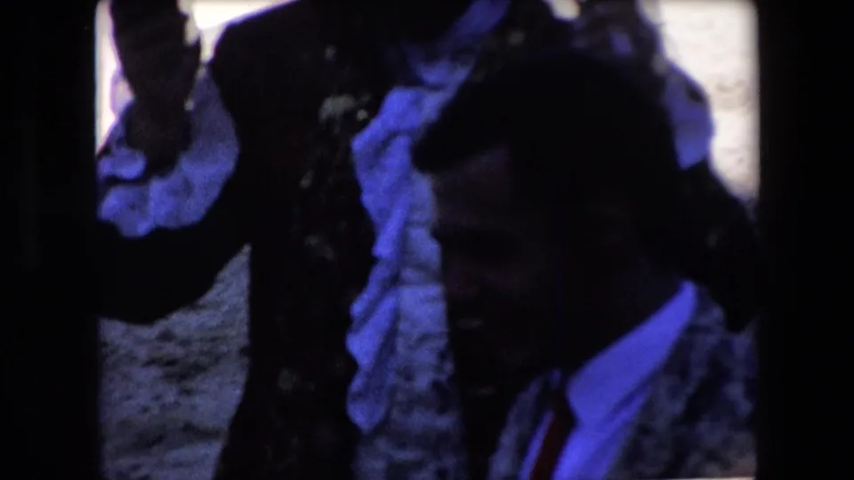 A dim 1971 Barcelona frame shows partially obscured men and a dark bullfighting costume shape near the camera, with blue color cast and heavy shadow.