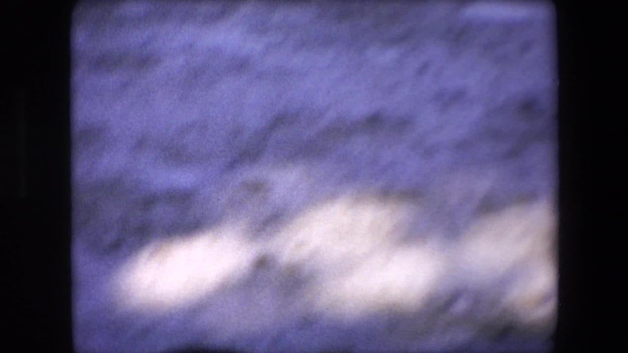 The final frame shows a soft, nearly abstract view of sandy arena ground with shadowed areas and bright exposure patches, consistent with handheld 8mm movement.